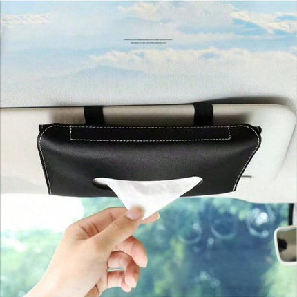 Car visor tissue holder with a hand pulling out a tissue against a blurred outdoor background