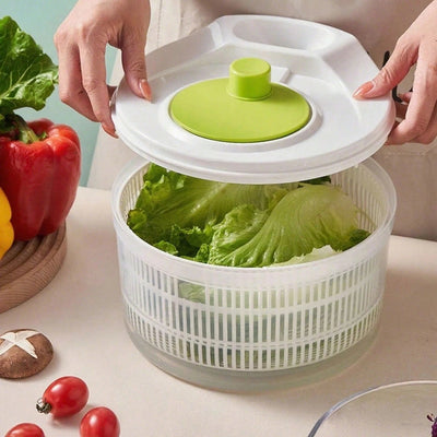 Person holding a salad spinner with lettuce, surrounded by vegetables on a table.